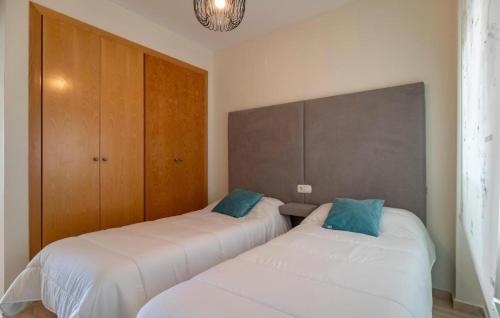 2 Betten in einem Zimmer mit weißer Bettwäsche und blauen Kissen in der Unterkunft Almerimar Golf y Playa in Almerimar