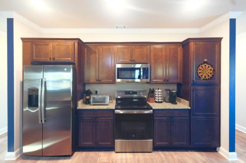 a kitchen with wooden cabinets and a stainless steel refrigerator at Cozy & Spacious 2 King Beds Near UGA & Downtown in Athens