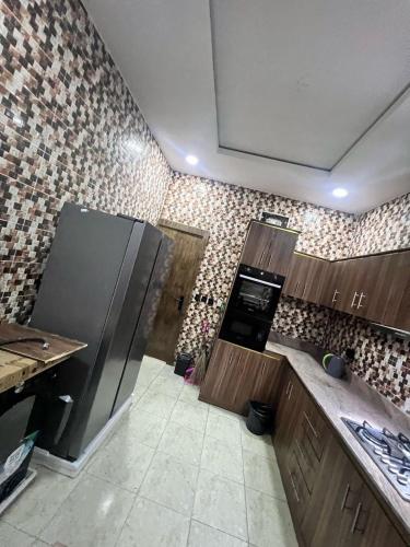 a kitchen with a refrigerator and a tile wall at Luxury 4BR Apt 5Min to LCC with Pool in Secured Estate in Ibeju
