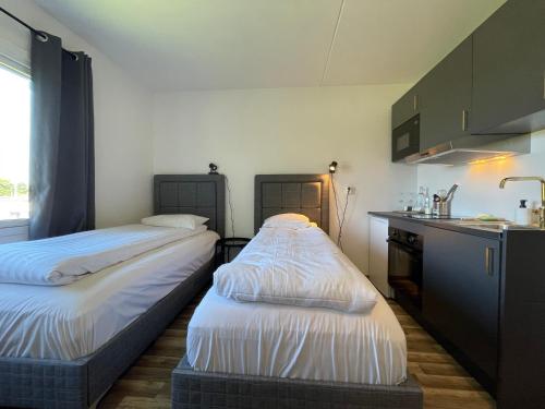 two beds in a small room with a kitchen at Injoy Classic Hotel Halmstad in Halmstad
