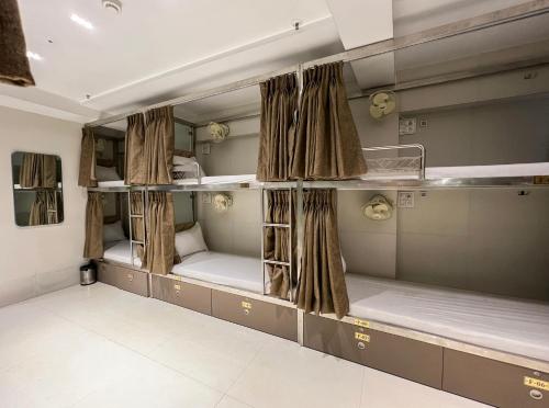 a room with three bunk beds with curtains at APEX STAY Rooms & Dormitory in Mumbai