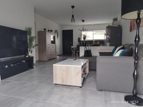 un salon avec un canapé et une télévision dans l'établissement Maison de famille, à Saint-Julien-des-Landes