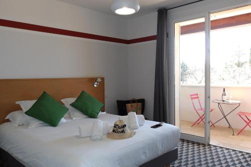 a bedroom with a bed with green pillows and a balcony at La Maison des Ocres - Provence in Roussillon