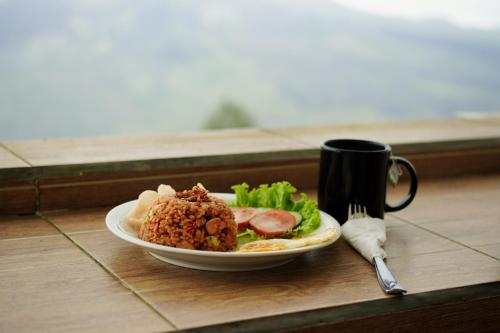 a plate of food on a table next to a coffee mug at The Kayuan in Kintamani