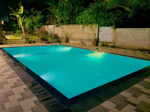 a large blue swimming pool at night at Dhanaya Safari Home in Udawalawe