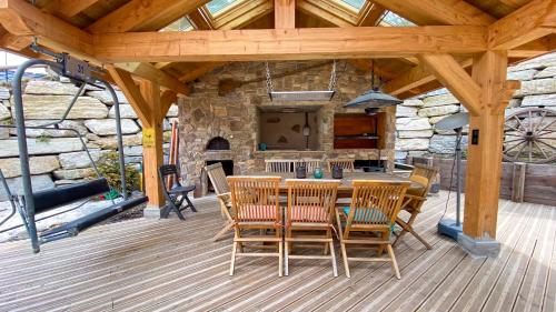 une terrasse en bois avec une table, des chaises et une cheminée dans l'établissement Chalet Grand Area, à Briançon