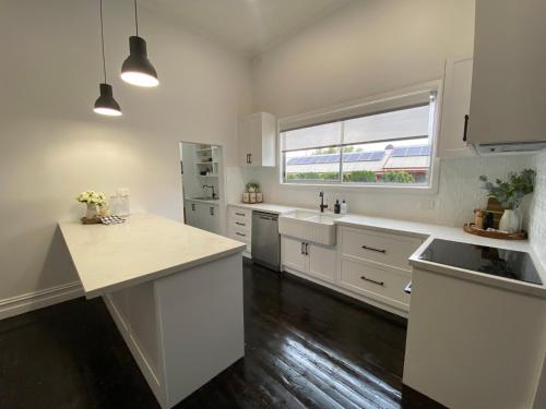 een grote keuken met witte kasten en een raam bij Daisy Cottage, 4 bedrooms, close to CBD in Golden Square