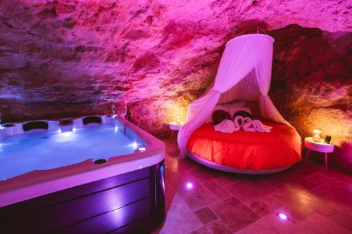 - une chambre avec une baignoire et un lit dans une grotte dans l'établissement La Grotte Fleurie - Classé 5 Étoiles, à Mussidan