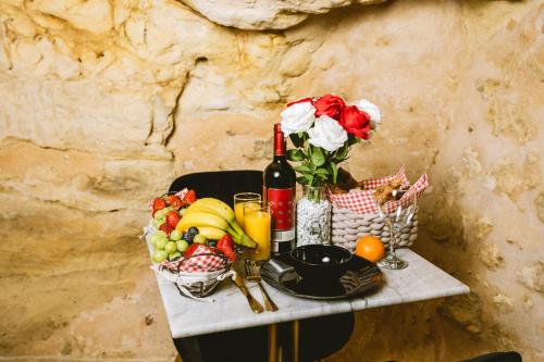 une table avec un bouquet de fruits et une bouteille de vin dans l'établissement La Grotte Fleurie - Classé 5 Étoiles, à Mussidan