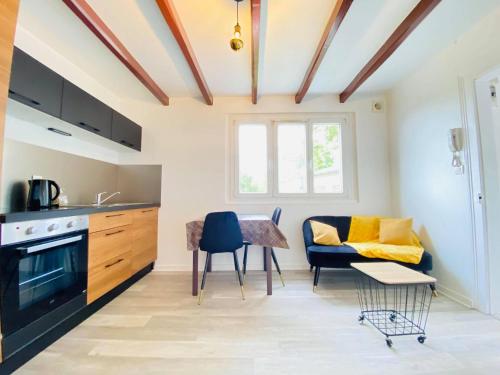 a kitchen and living room with a couch and a table at Appartement Cosy avec jardin chaleureux in Laon