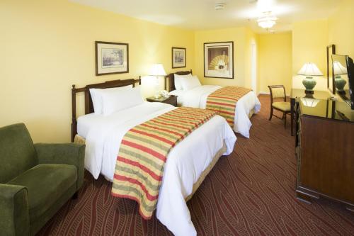 una habitación de hotel con 2 camas y una silla en Campbell Inn Hotel, en Campbell