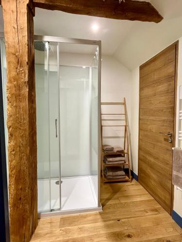 La salle de bains est pourvue d'une douche en verre et d'une porte en bois. dans l'établissement Domaine de la Bigottière, Chambres d'hôtes, à Montigné-le-Brillant