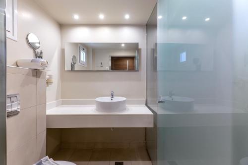 a white bathroom with a sink and a mirror at Akti Coast Club in Marmari