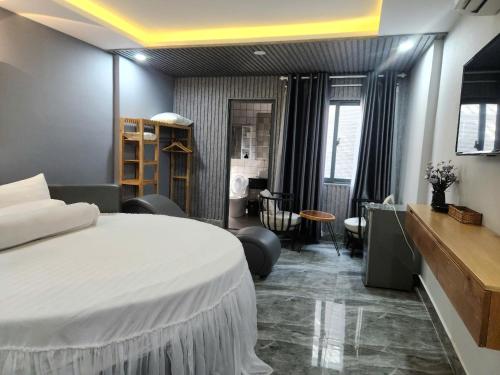 a bedroom with a large white bed and a desk at Hotel & Homestay LABUBU in Vung Tau