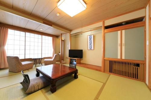 a living room with a coffee table and a tv at Ryokan Biyunoyado in Yamanouchi