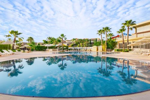 a swimming pool at a resort with palm trees at Unique Residence Hotel Golf and Spa in Soke