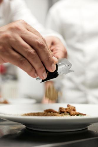 a person holding a knife over a plate of food at La Locanda Del Capitano in Montone