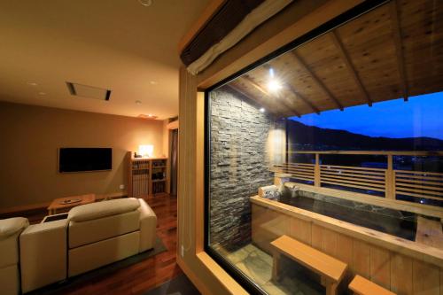 a living room with a large window and a couch at Ryokan Biyunoyado in Yamanouchi