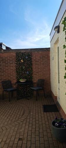 a patio with two benches and a brick wall at De beukenboom Bed and Breakfast in Geleen