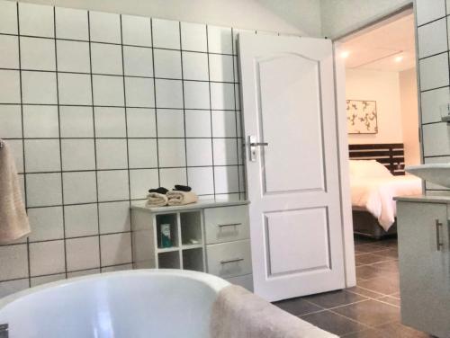 a bathroom with a bath tub and a bedroom at Riverise Guesthouse in Maun