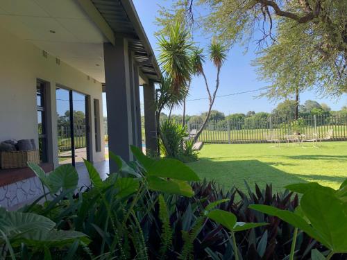 a porch of a house with a lawn at Riverise Guesthouse in Maun