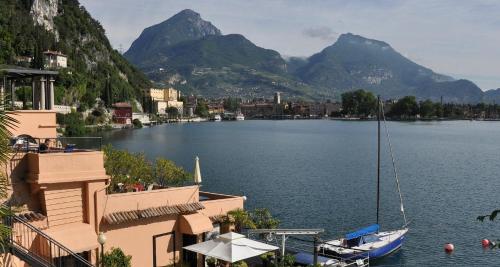 a boat on a lake with mountains in the background at Excelsior Lake View in Riva del Garda