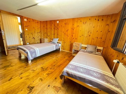 two beds in a room with wooden walls and wooden floors at AlpenHaus, farmhouse in Triesenberg