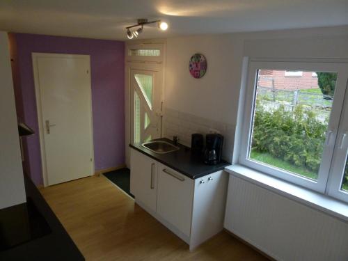 eine kleine Küche mit einem Waschbecken und einem Fenster in der Unterkunft Ferienhaus Rheiderland in Ditzumerverlaat