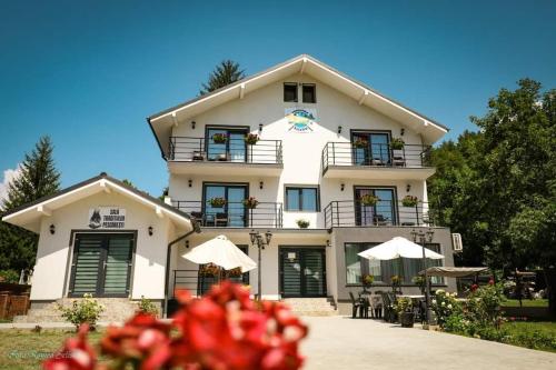 a large white building with tables and umbrellas at Pensiunea Silver in Caciulata