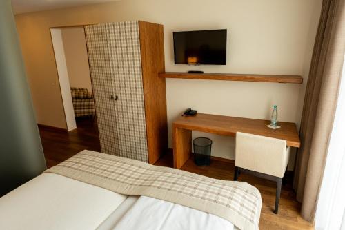 a bedroom with a bed and a desk and a television at Restaurant Hotel Zum Storchen in Waldkirch
