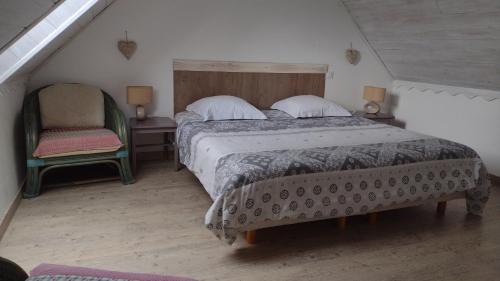 a bedroom with a large bed and a chair at La ferme de la Cavalerie in Saint-Gonnery