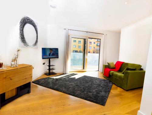 un salon avec un canapé vert et une télévision dans l'établissement Peninsula Life- Stylish Greenwich 1bed Flat, à Londres