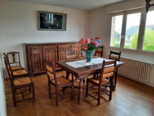 une table à manger et des chaises avec un vase de fleurs dans l'établissement Family house for 7, à Perros-Guirec