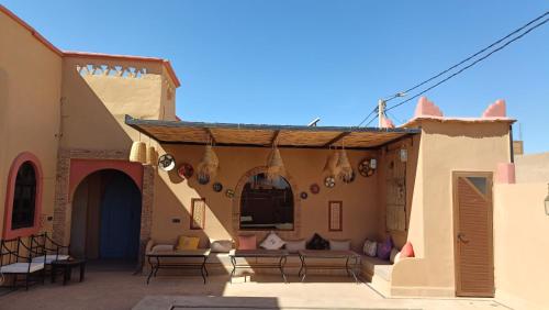 an outdoor patio with couches and tables and chairs at Riad Dar Poublanc in Merzouga