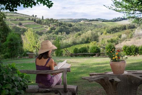 a woman sitting on a bench reading a book at Podere Felceto in Panzano