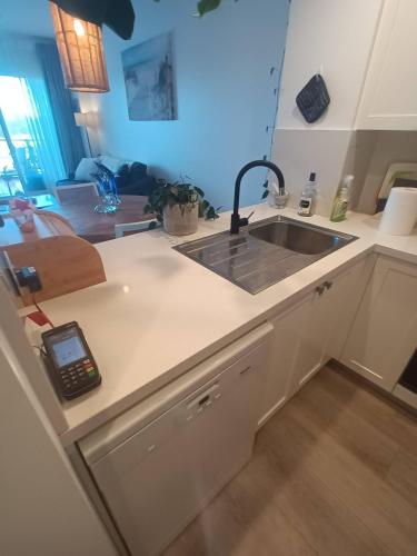 a kitchen with a sink and a cell phone on the counter at Backpackers Waterfront Stay at Shoal Bay Stayz with Dave Stays in Shoal Bay