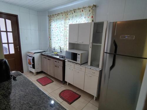 a kitchen with a refrigerator and a microwave at Apto com jeito de casa entre o mar e a montanha in Florianópolis