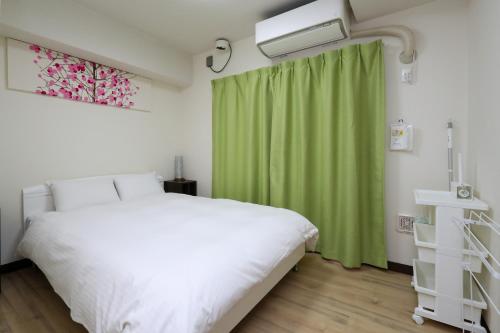 金沢市にあるゲストルーム金沢心音 Guest Room Kanazawa COCONEのベッドルーム(白いベッド1台、緑のカーテン付)