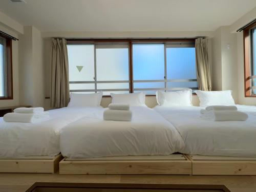 2 camas blancas grandes en una habitación con ventanas en Ikeda Ueno 401 Quad room, en Tokio