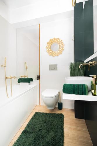 a bathroom with a white toilet and a green rug at Gold Apartments Centrum in Częstochowa