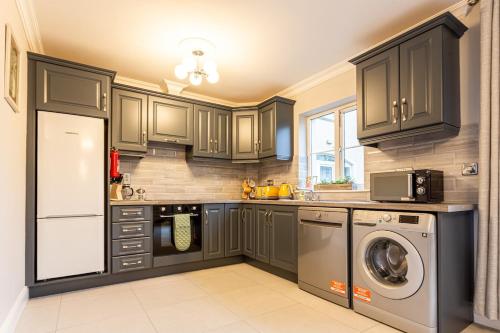 a kitchen with gray cabinets and a washer and dryer at No 31 Killarney Holiday Village in Killarney