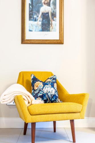 a yellow chair with a blue and white pillow on it at No 31 Killarney Holiday Village in Killarney