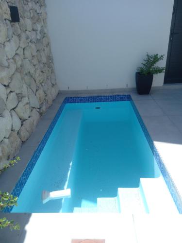 a large blue swimming pool in front of a stone wall at Atlantic Sands Beachfront Estate in Velddrif