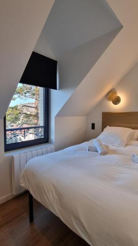 une chambre avec un grand lit blanc avec une grande fenêtre dans l'établissement La Villa Oswar Wilde, à Saint-Martin-Plage