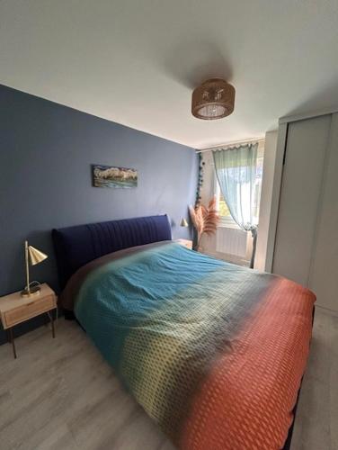 - une chambre avec un lit coloré dans l'établissement Appartement coquet avec jardin proche de la mer, à Ouistreham