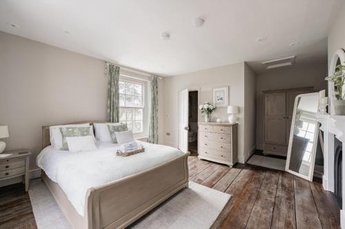 a bedroom with a large white bed and wooden floors at Sutton Hall, Norfolk in Hickling
