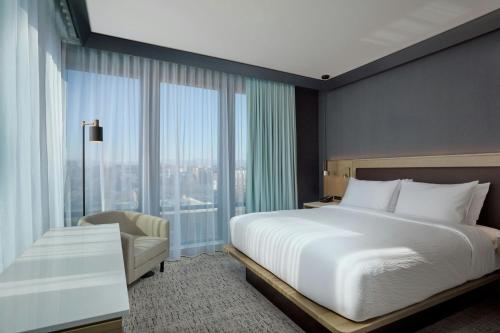 a bedroom with a large white bed and a chair at Courtyard by Marriott Denver Downtown West in Denver