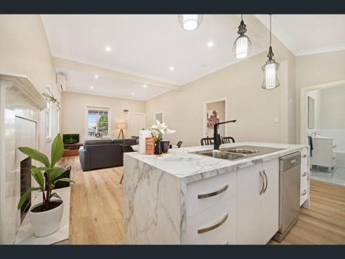 a kitchen with a marble counter top and a living room at Eton Cottage - Central Boutique Stay in Toowoomba