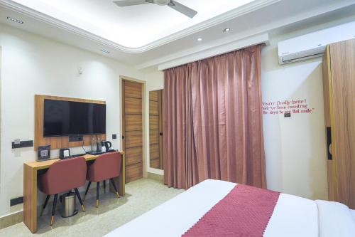 a hotel room with a bed and a desk with a television at Orsom Stays Sassy Sector 53 in Gurgaon