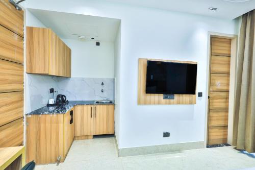 a kitchen with a sink and a tv on a wall at Orsom Stays Sassy Sector 53 in Gurgaon